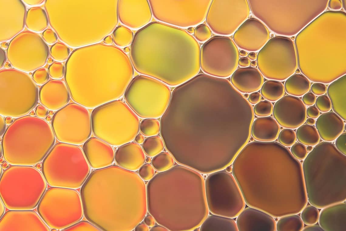 Dr. Ruth Blog: Mineralöle in Kosmetik - Abstrakte Öltropfen, dicht nebeneinanderliegend in gelb, rot, grün und braun verlaufendem Farbmuster